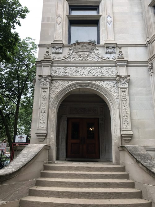Ornate stone archway over steps to a double door